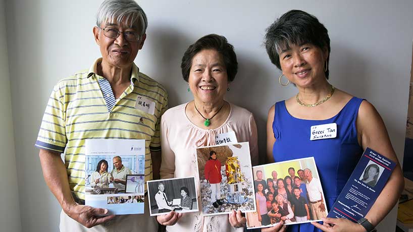 Tan family holding family photos