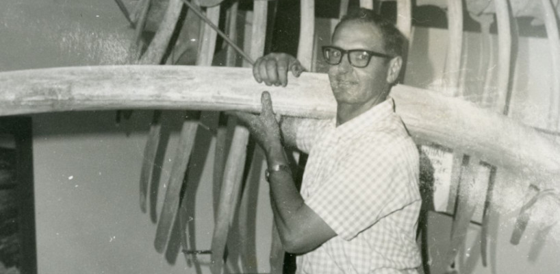 black and white photo of man with glasses holding a whale rib